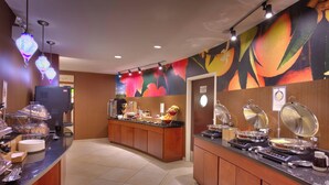A buffet area with a counter, food display, and a wall with a fruit mural. - Fairfield Inn & Suites by Marriott Boise Nampa (Nampa)