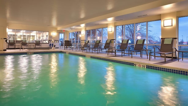 An indoor swimming pool with clear water, surrounded by lounge chairs and large windows offering views of the outside. - Fairfield Inn & Suites by Marriott Boise Nampa (Nampa)