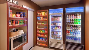 A kitchenette with a microwave, a shelf of snacks, and a refrigerator stocked with beverages and food items. - Fairfield Inn & Suites by Marriott Boise Nampa (Nampa)