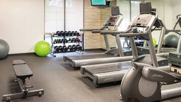 A gym with treadmills, dumbbells, and exercise balls.