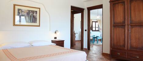A bedroom with a bed, a nightstand, a wooden wardrobe, and a framed picture on the wall.