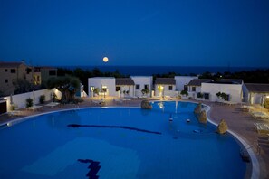 Una piscina al aire libre, sombrillas, tumbonas