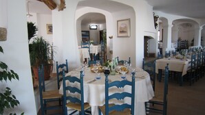 A dining area with round tables, blue chairs, and white tablecloths. - Hotel Nuraghe Arvu (Dorgali)
