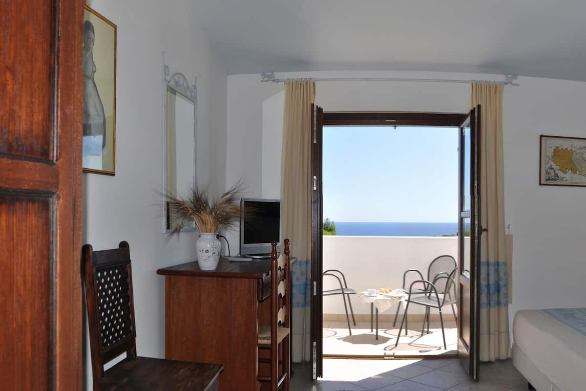 Un dormitorio con cama, mesita de noche y vistas al mar.