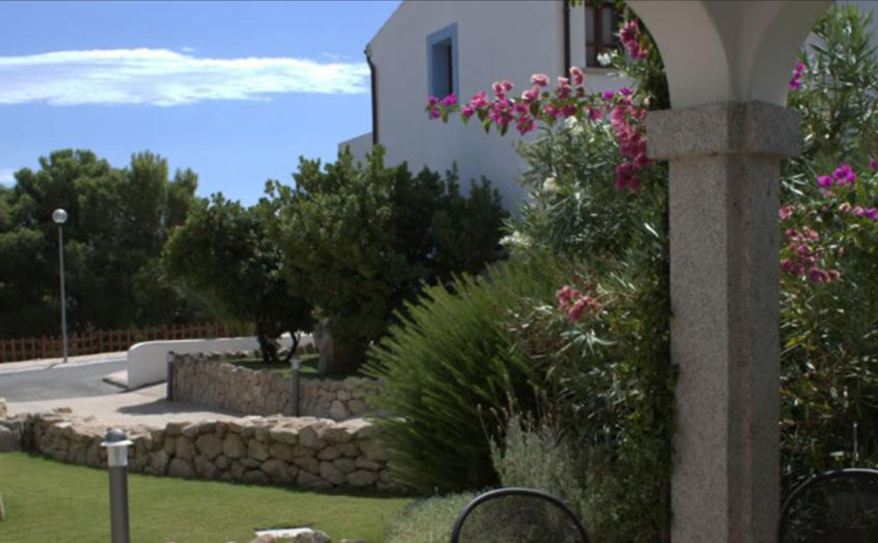 A building with a stone wall, a grassy area, and pink flowers.