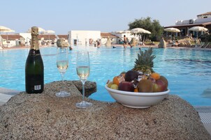 Una piscina al aire libre, sombrillas, sillones reclinables de piscina