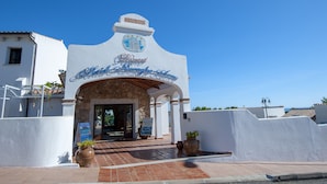 The entrance to the Hotel de Monterrey with a stone archway and a clear blue sky above. - Hotel Nuraghe Arvu (Dorgali)