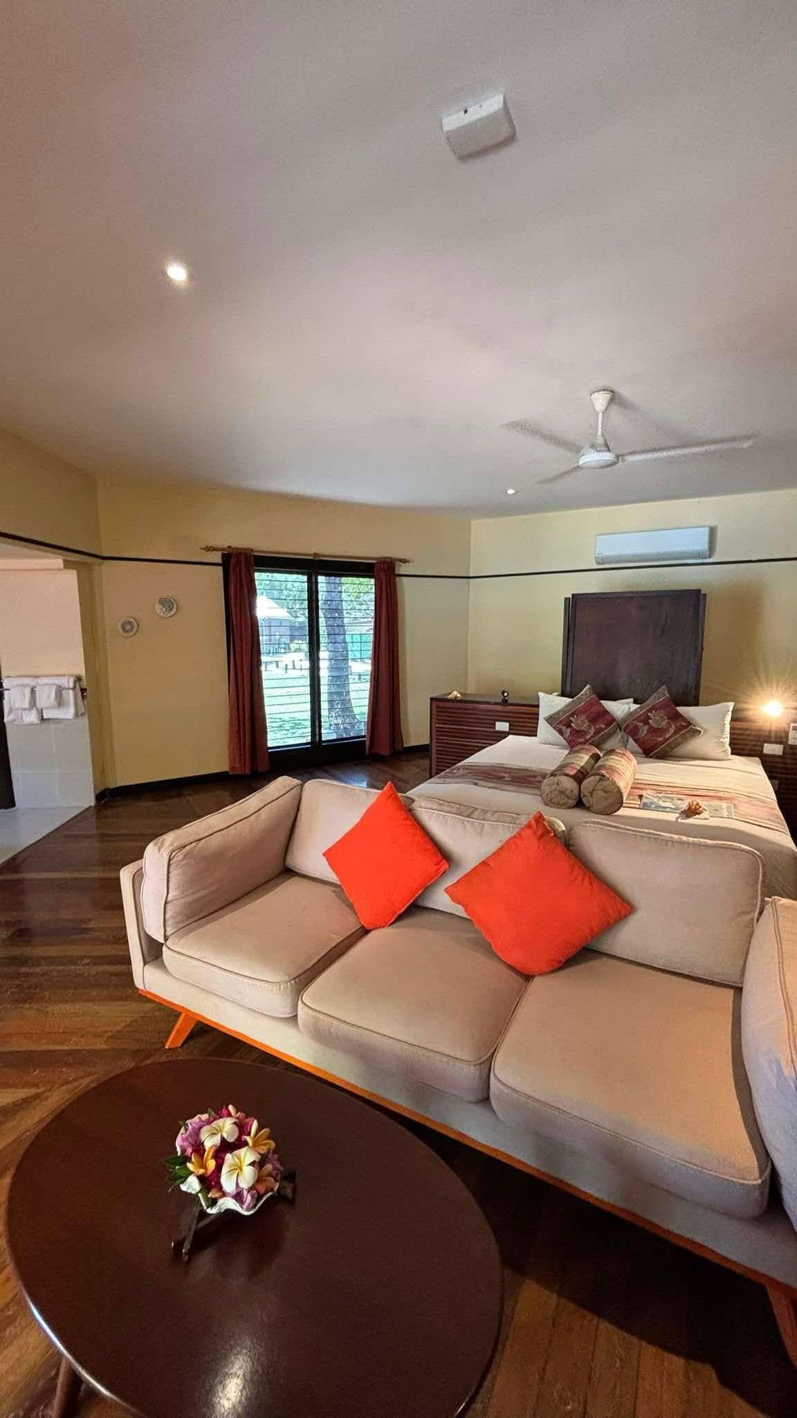 Ein modernes Hotelzimmer mit einer großen Couch, einem runden Couchtisch und einem Bett mit Kissen.