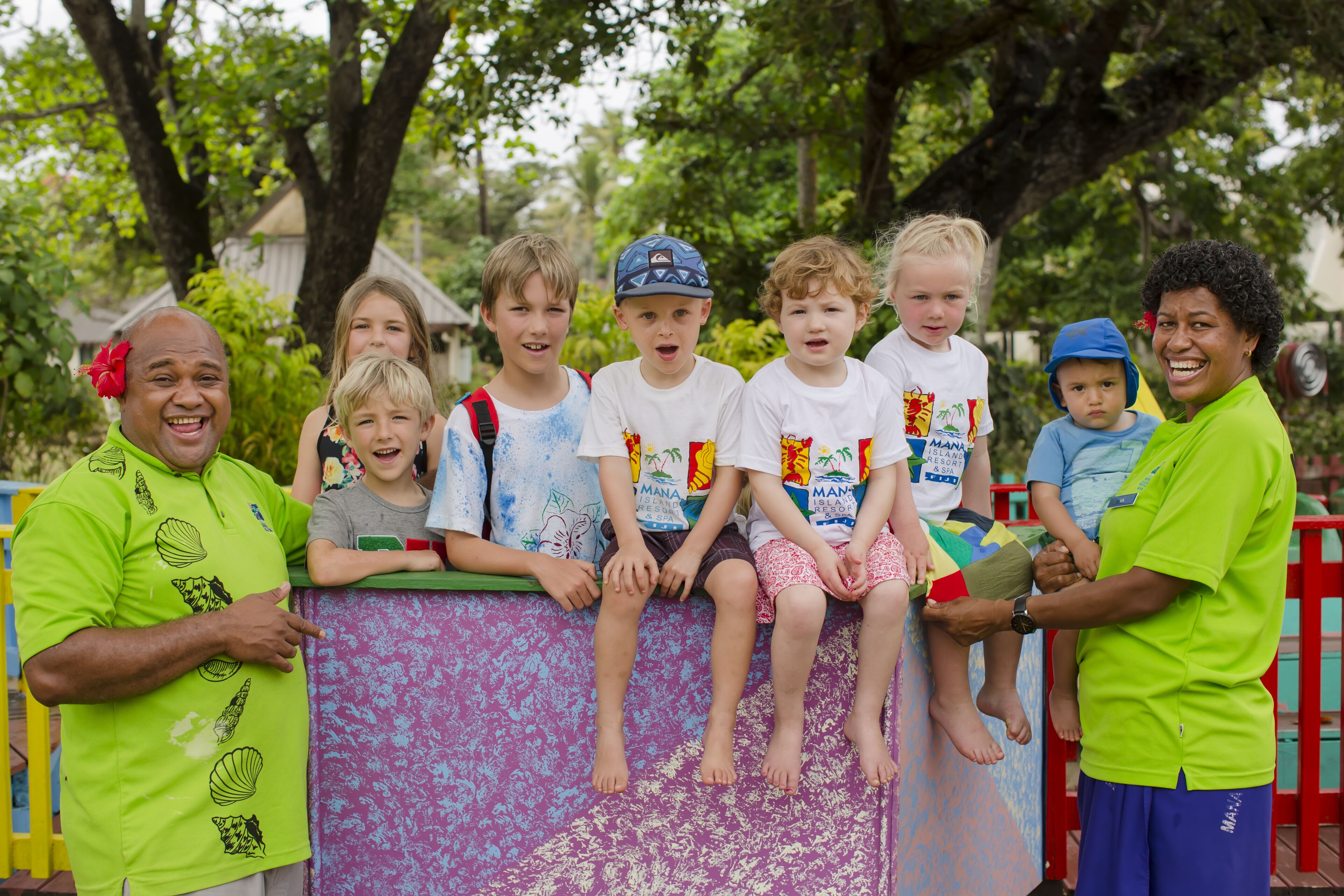 A group of people sitting on a colorful play structure outdoors.