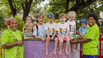 A group of people sitting on a colorful play structure outdoors.