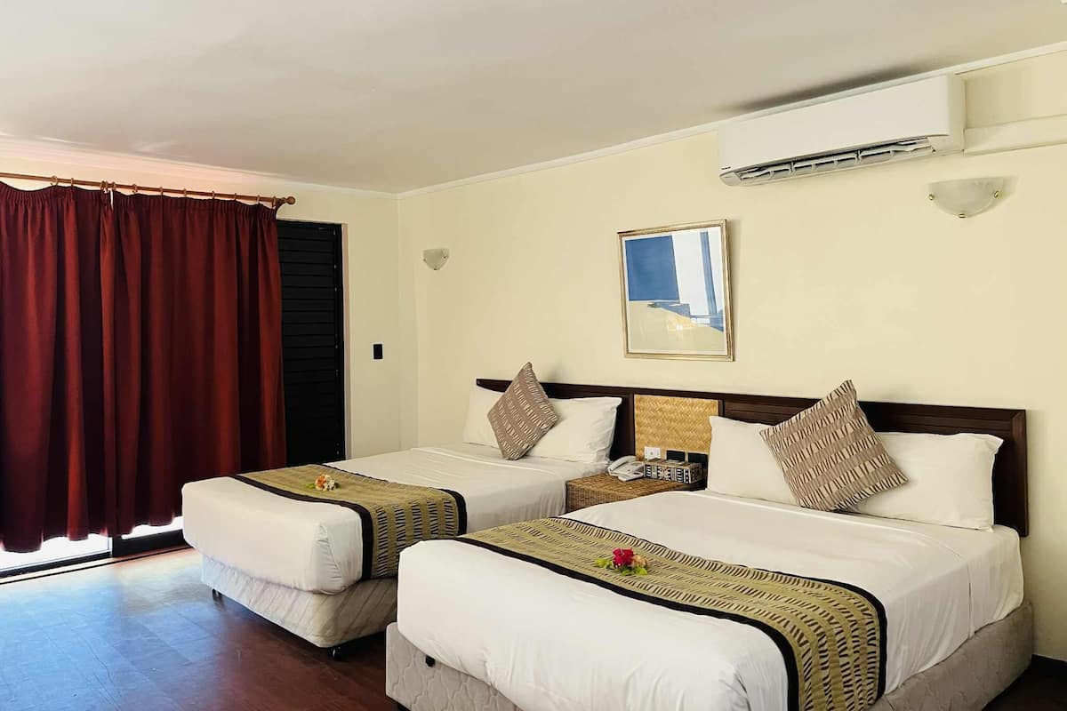 A hotel room with two beds, a large window with curtains, an air conditioning unit, and a framed picture on the wall.