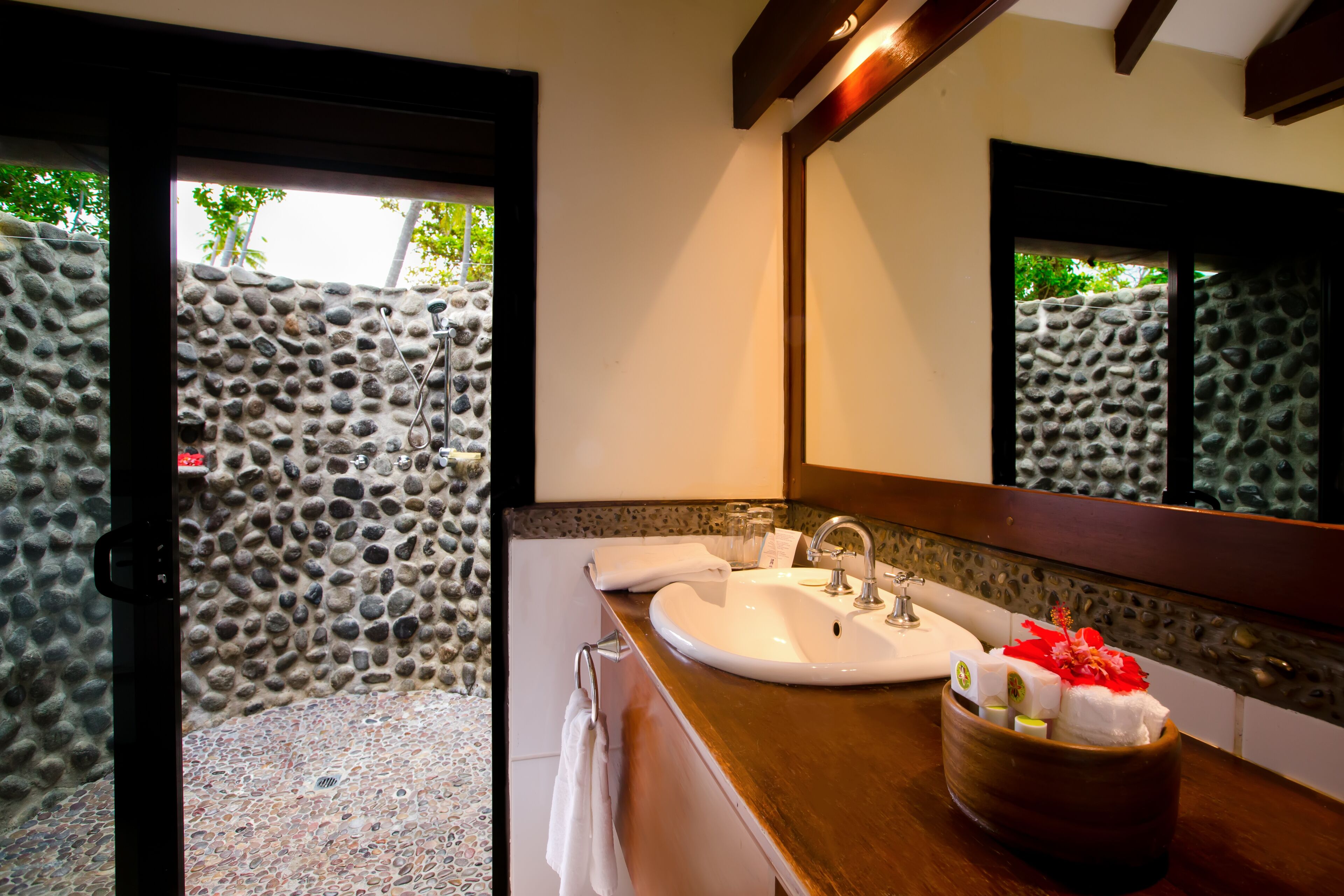 A bathroom with a stone wall, a wooden countertop, a sink, and a mirror.