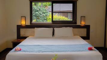 A neatly made bed with a blue and white striped bedspread, two bedside lamps, and a window with blinds.