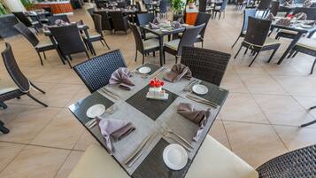 Un vaste espace intérieur aménagé pour les repas, avec de nombreuses tables, et agrémenté d’un élément décoratif central.