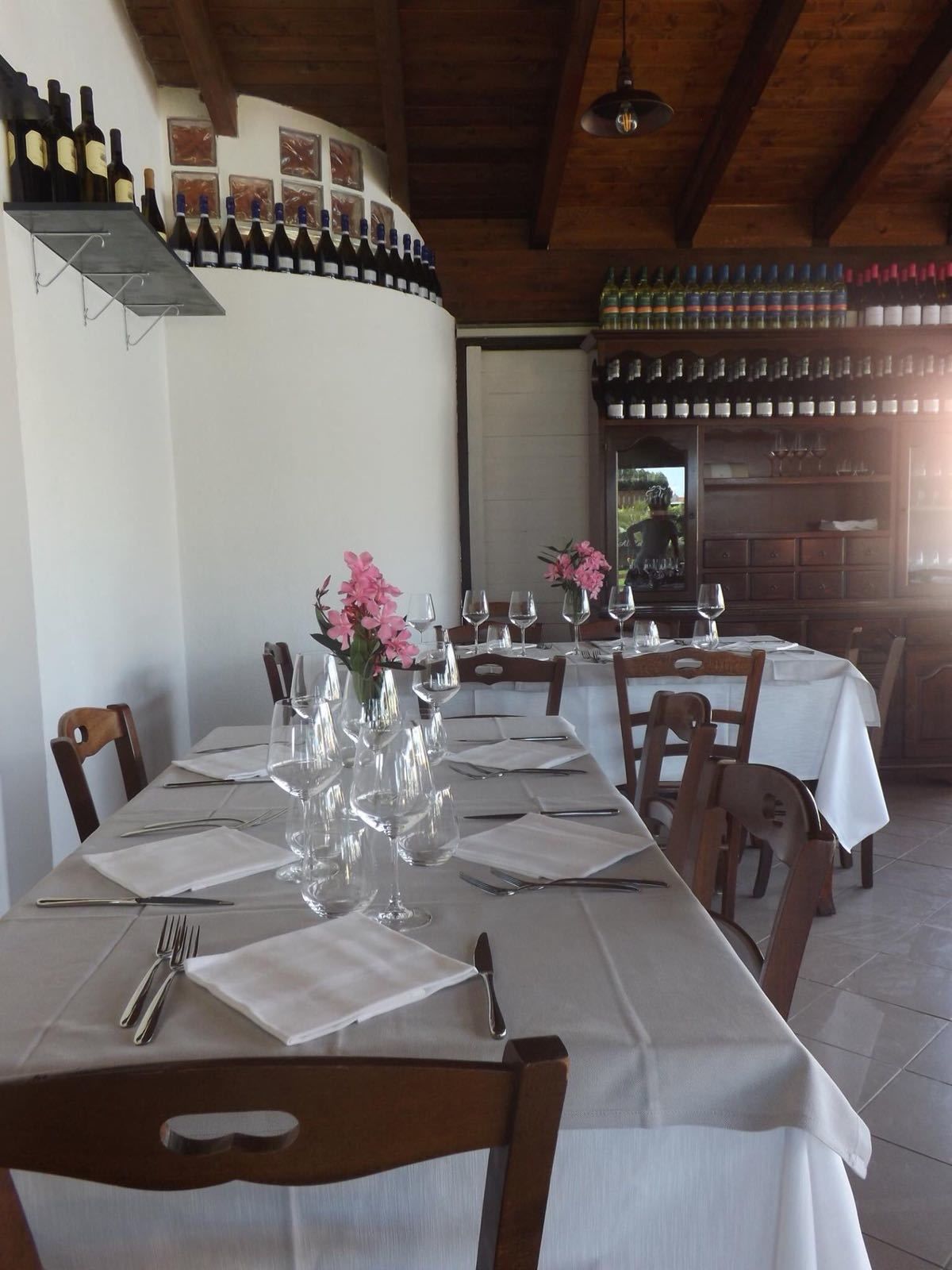 Un restaurant où les tables sont dressées, où l’on peut voir des bouteilles de vin sur des étagères et où le plafond est fait de bois brut.