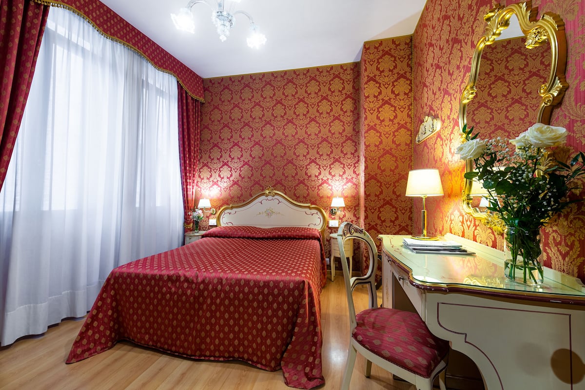 Ein Hotelzimmer mit einem großen Bett, einem Schminktisch mit Spiegel und einem Schreibtisch mit Lampe.