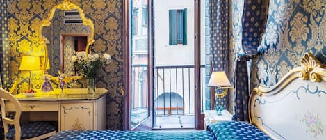 Una habitación con cama, escritorio y silla. Se ve una ventana con vista a la calle.
