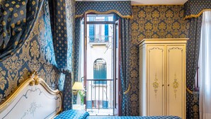 A bedroom with a bed, a wardrobe, and a view of the outside balcony. - Hotel Al Gazzettino (Venice)
