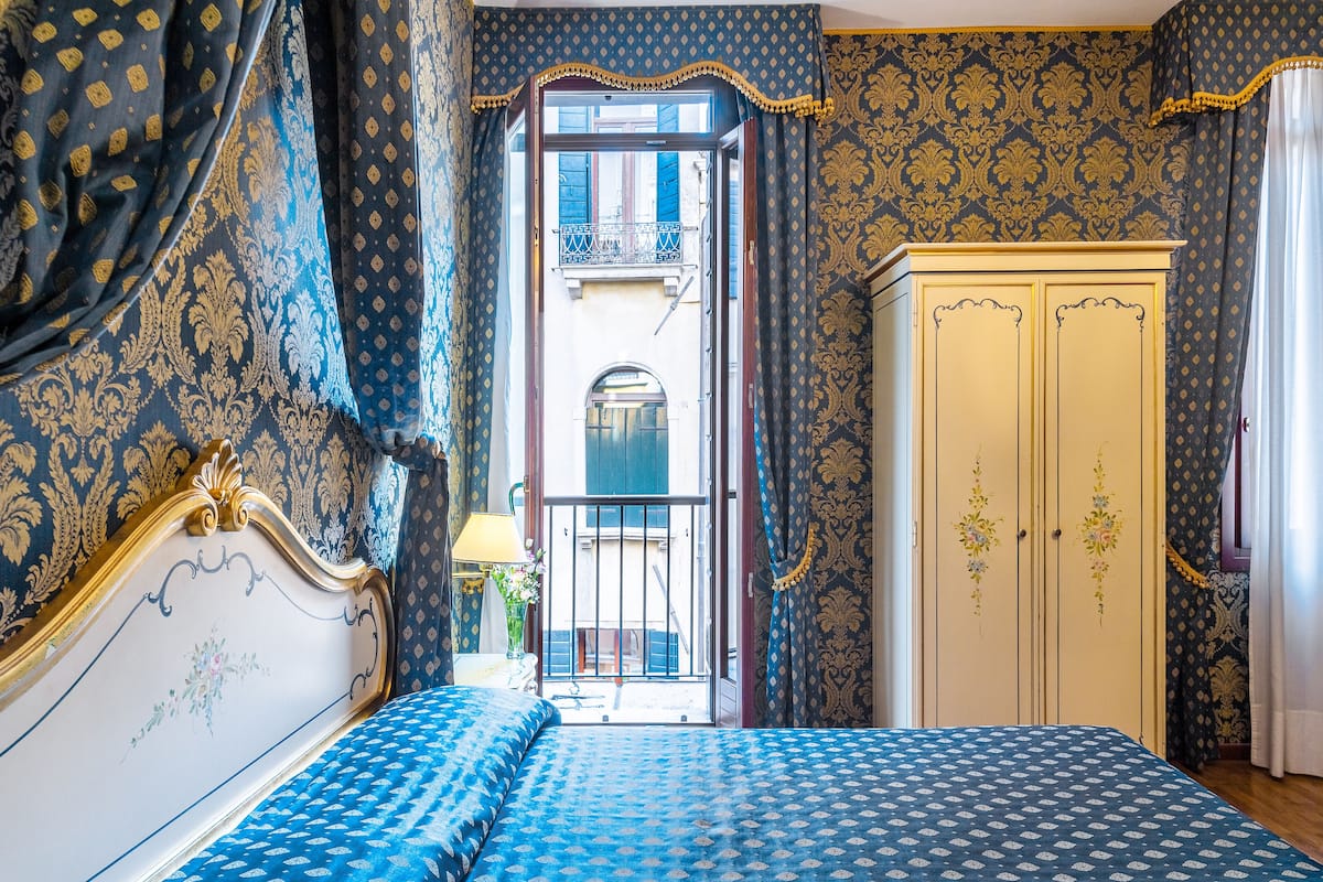 Ein Schlafzimmer mit Bett, Kleiderschrank und Blick auf den Balkon.