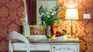 A vintage-style vanity with a mirror, a vase with flowers, a bowl of fruit, and a lamp. - Hotel Al Gazzettino (Venice)