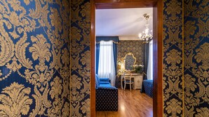 A room with ornate blue wallpaper, a wooden floor, a bed, a desk, and a chair. - Hotel Al Gazzettino (Venice)