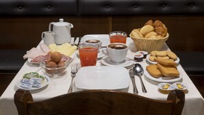 A breakfast table with a variety of food items, a coffee cup, and three wall-mounted clocks. - Hotel Al Gazzettino (Venice)