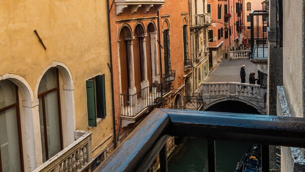 A narrow canal with buildings on either side, featuring balconies and arched windows. - Hotel Al Gazzettino (Venice)