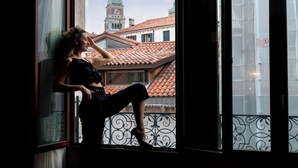 A person sitting by a window with a view of a building with a green spire and red-tiled roofs. - Hotel Canaletto (Venice)