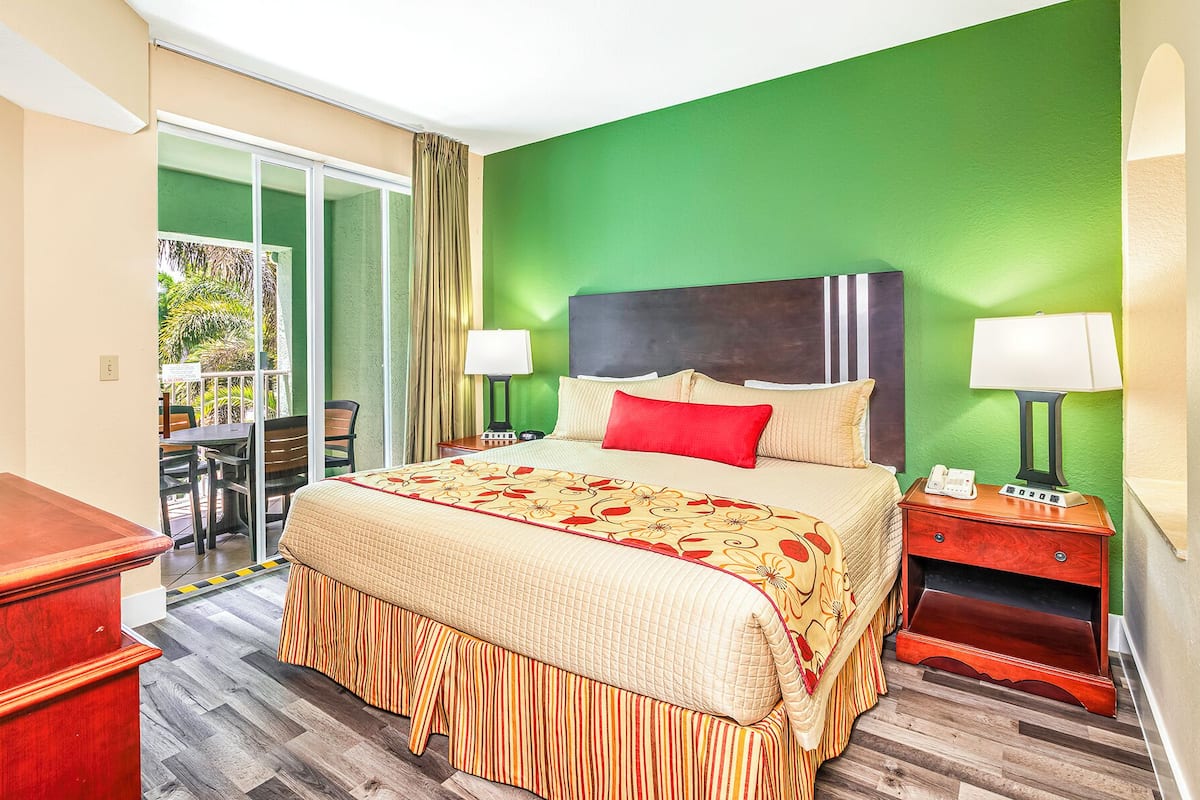 A hotel room with a bed, two bedside tables with lamps, a wooden desk, and a view of the outdoors.
