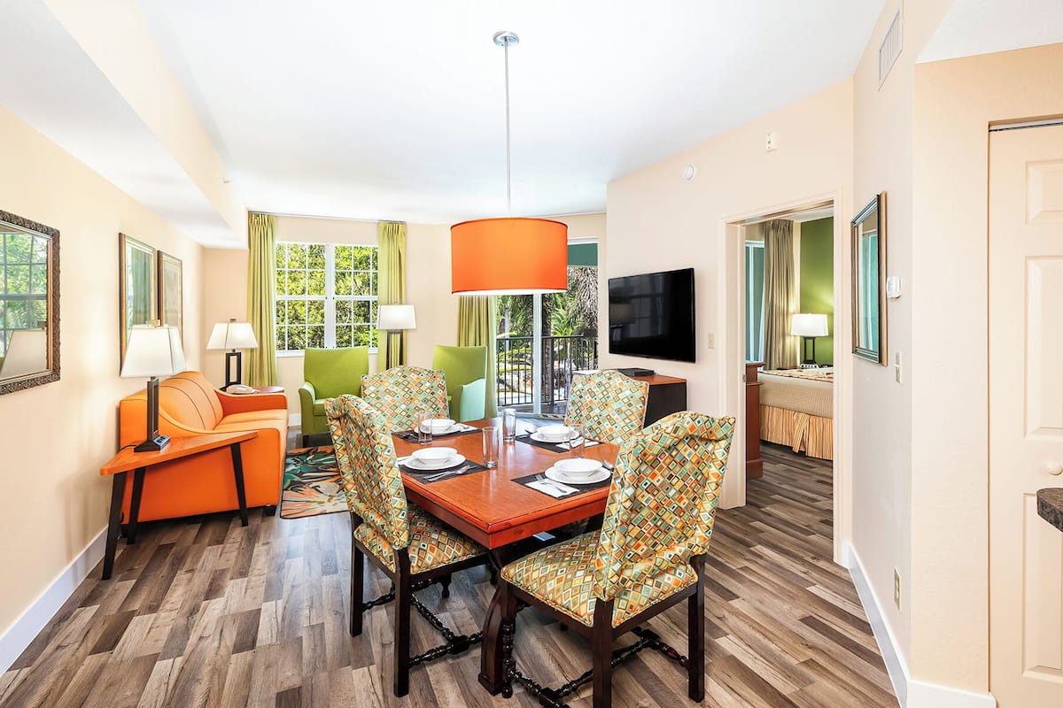 A dining area with a wooden table, patterned chairs, and a large orange pendant light.