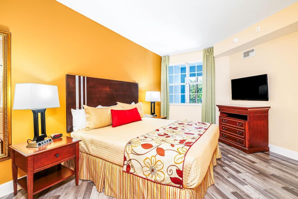 A hotel room with a bed, bedside tables, a TV, and a dresser.