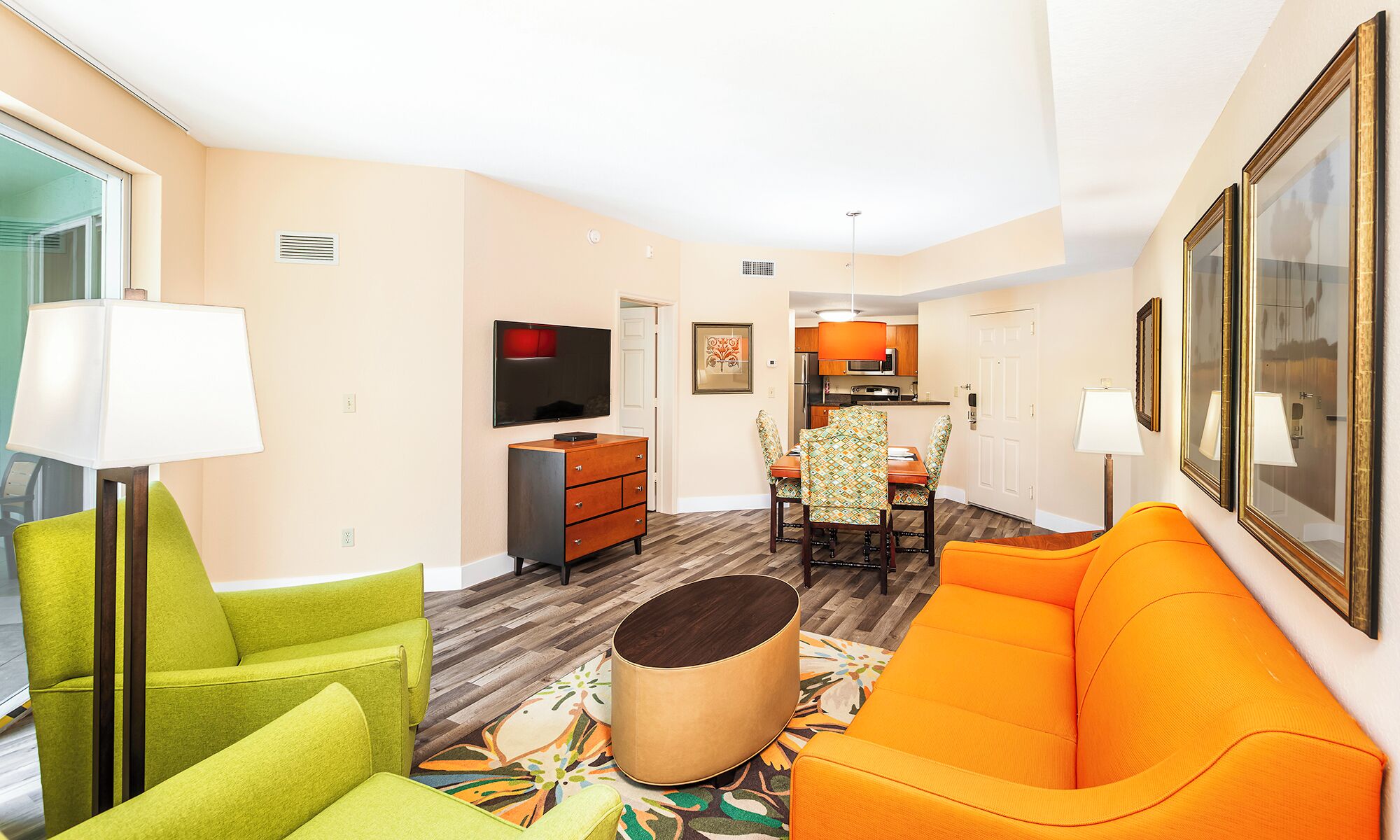 A modern living room with a sofa, a chair, a lamp, a TV, and a dining area with a table and chairs.