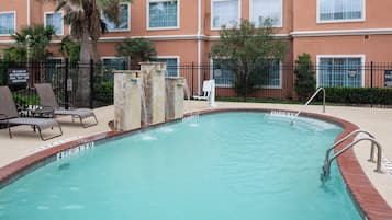 A swimming pool with a 4ft depth marker, surrounded by lounge chairs and a palm tree.