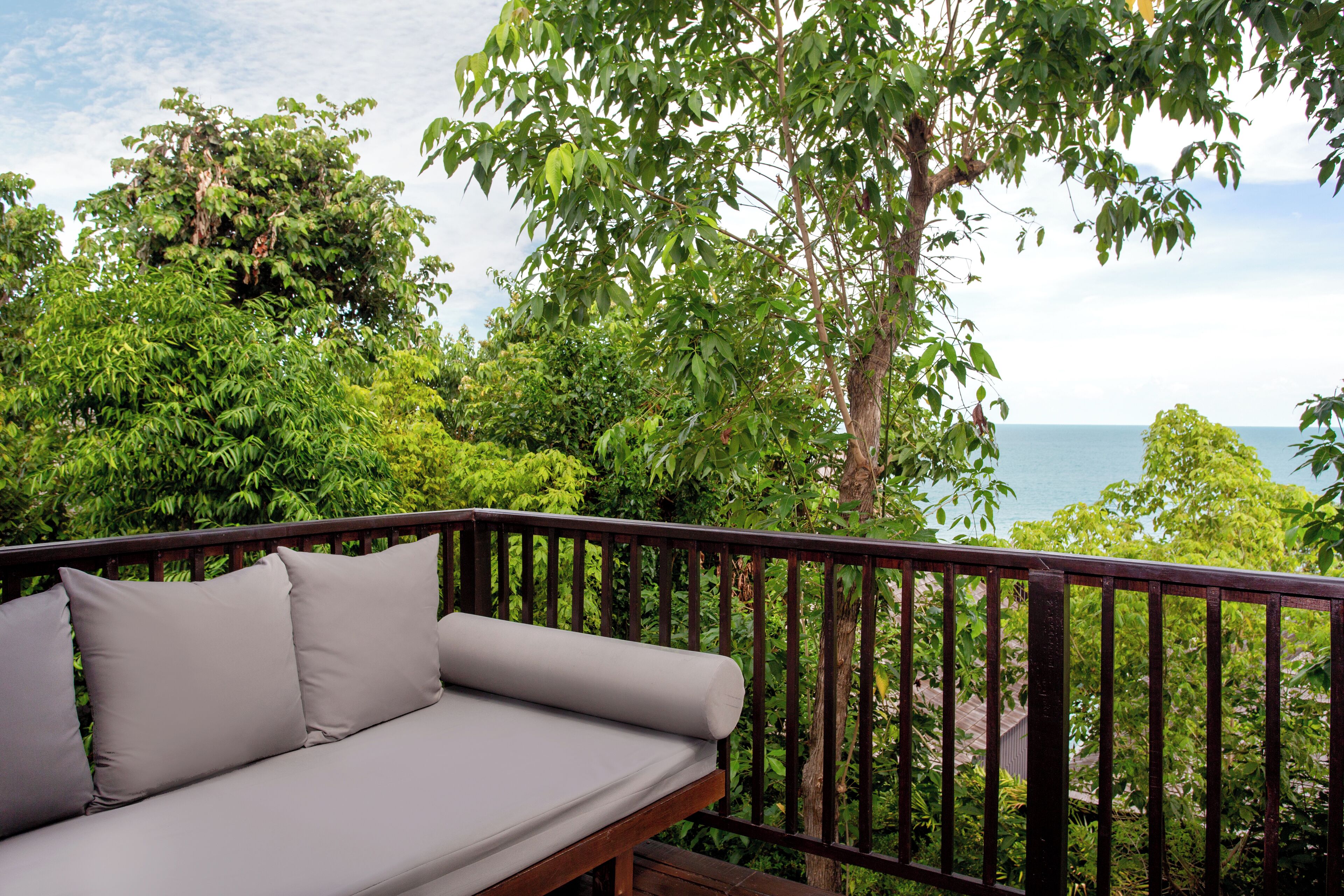 A wooden deck with a grey sofa and a metal railing.
