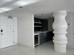 A modern kitchen with a built-in oven, a sink, and a large white column.
