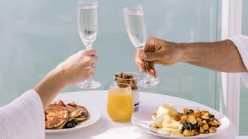 A dining table with breakfast plates, two glasses of champagne, and a glass of orange juice.