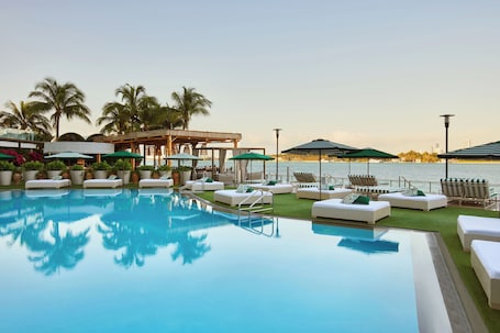 Una piscina al aire libre, camas de piscina con cargo, sombrillas