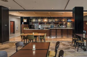 Un restaurante moderno con zona de bar, techo de madera y diferentes disposiciones de asientos.