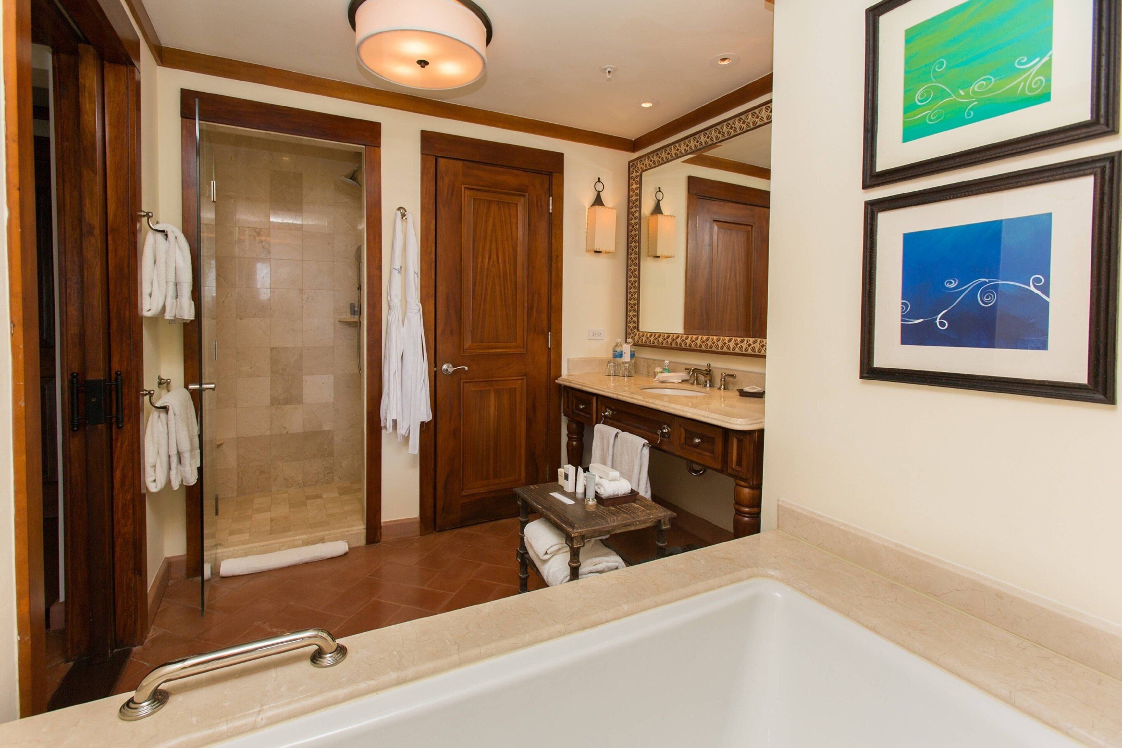 A bathroom with a bathtub, a shower, and a vanity with a mirror.