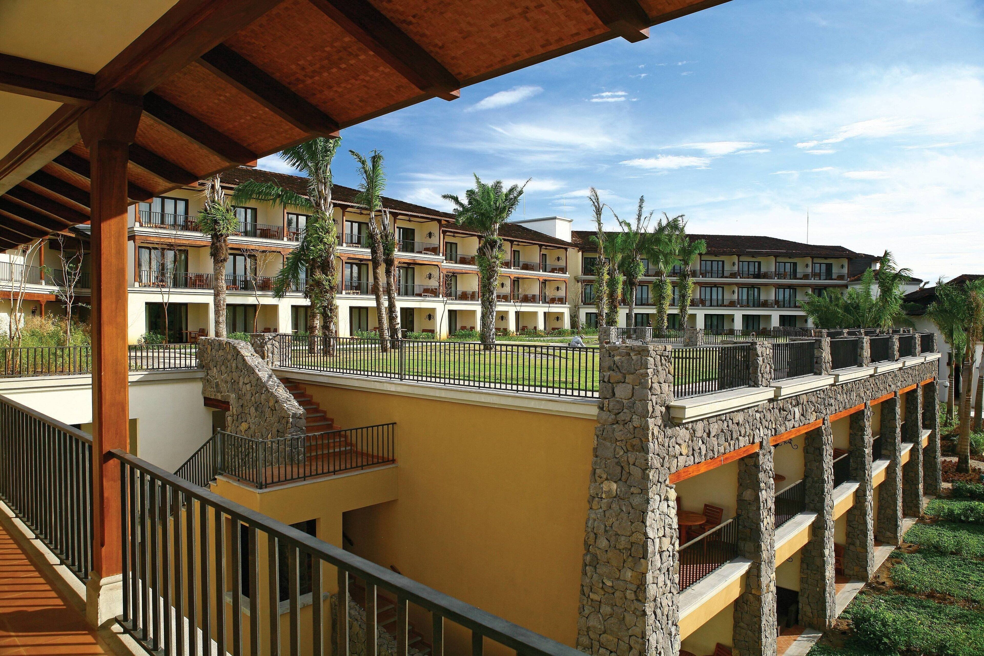 A multi-story hotel with balconies, stone pillars, and a covered walkway.
