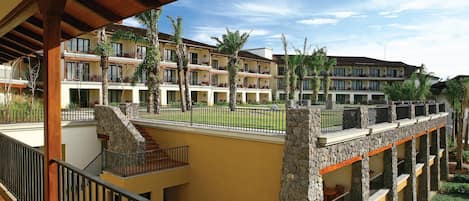 A multi-story hotel with balconies, stone pillars, and a covered walkway.