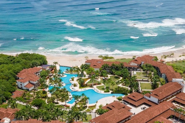 A resort with a central swimming pool, beachfront villas, and a beach.