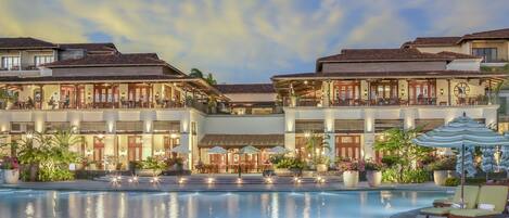 A hotel with a pool, outdoor seating, and a covered area.