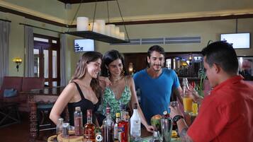 Una zona de bar con mostrador de madera, varias botellas y una pantalla de televisión.