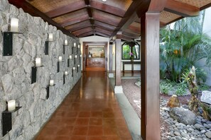 A stone-walled hallway with recessed lighting, leading to a wooden reception desk.