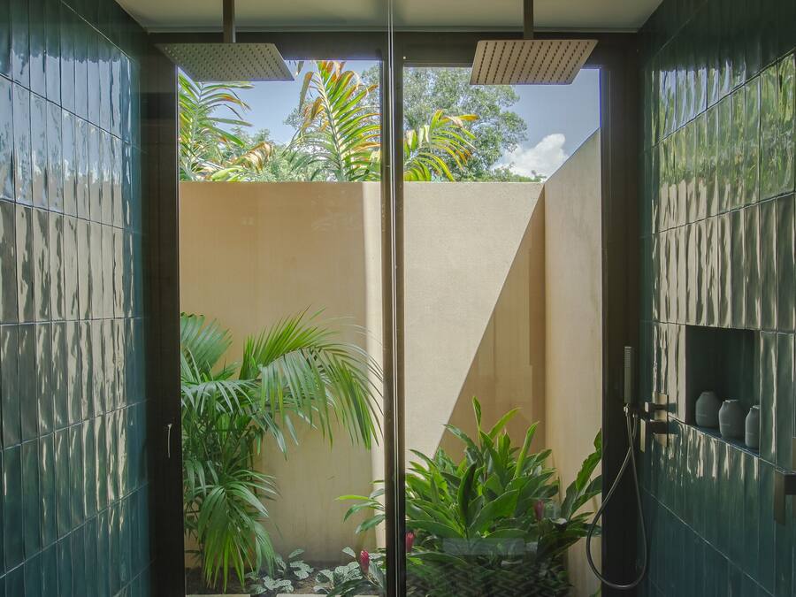 A modern bathroom with a glass door leading to a small garden area.