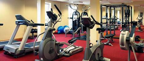A gym with various cardio machines, weightlifting equipment, and exercise balls.