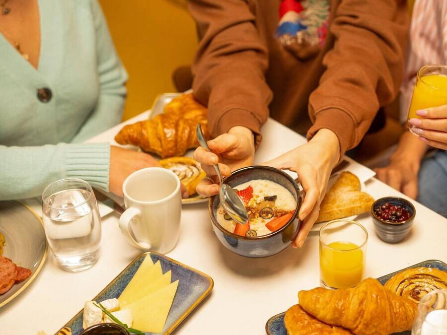 A breakfast setting with croissants, a bowl of soup, and a glass of orange juice.