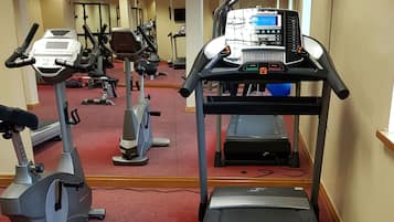 Un gimnasio con cintas de correr, bicicletas estáticas y elípticas.