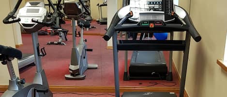 A gym with treadmills, stationary bikes, and elliptical machines.